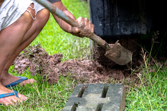 Thailand, February 28, 2562 : The elderly man is using his hand or hoe to dig the soil that is dirty. So that the stuck car can come out.