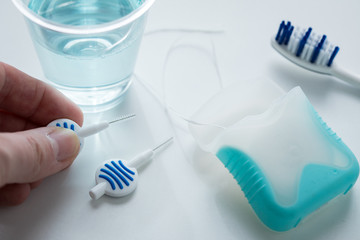 Fototapeta na wymiar Frau mit Zahnbürste, Mundwasser, Zahnseide und Blau Interdental Bürsten als Zubehör für tägliche Zahnpflege und Mundhygiene