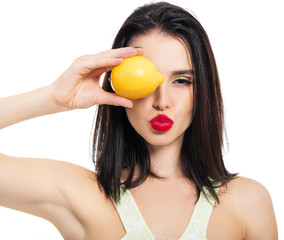 Excited beautiful girl holding lemon and posing in studio over white background.