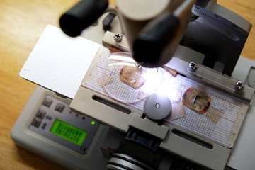 Professional ophthalmology instrument in clinic office and optics. Closeup of an optician drilling rimless eyeglasses in workshop. Optician measuring and preparing glasses