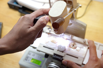 Professional ophthalmology instrument in clinic office and optics. Closeup of an optician drilling rimless eyeglasses in workshop. Optician measuring and preparing glasses