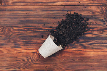 peat pot with earth black soil on a wooden background