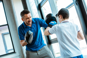 Fototapeta na wymiar boy in boxing gloves working out with father at gym
