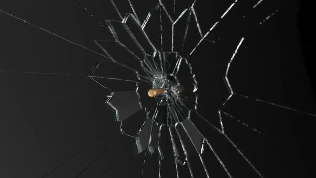 Slow-motion shot of a shiny bullet shattering a piece of transparent glass. 4KHD