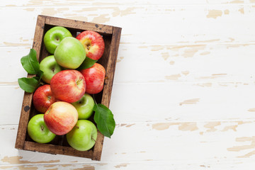 Green and red apples in wooden box