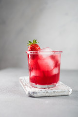 Srawberry soda drink with ice on grey background.