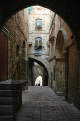 Fototapeta premium Arched street in old city of Jerusalem with two unidentifiable people walking