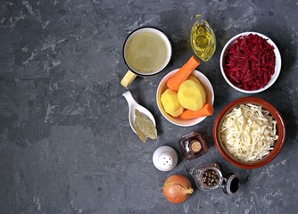 Ingredients for cooking borscht, traditional hot Russian soup with beetroot, cabbage and potatoes on a dark gray concrete background.