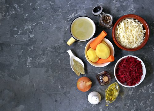 Ingredients for cooking borscht, traditional hot Russian soup with beetroot, cabbage and potatoes on a dark gray concrete background.