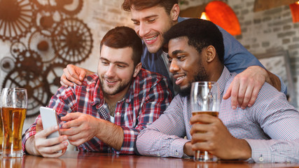 Men Having Fun. Friends Using Smartphone And Drinking Beer