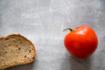 Pomidor czerwony z szypółkami na betonowym tle wraz z chlebem