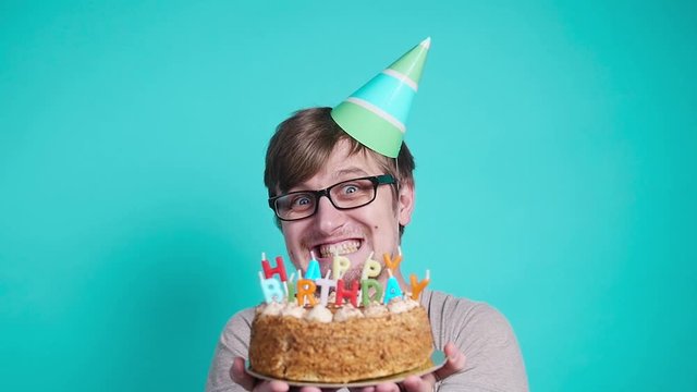 Concept of celebration and fun. Smiling happy crazy young man in party hat holding a birthday cake