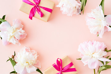 Flat lay composition with light pink peonies and gift box on a pink background