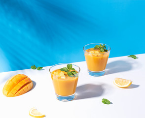 Fresh mango smoothie and ripe mango slice on color background. summer drink.