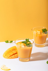 Fresh mango smoothie and ripe mango slice on color background. summer drink.