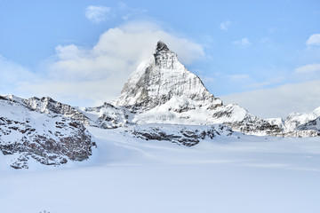 beautiful view of the Matterhorn from the ski slopes in the winter on a beautiful clear day. Blue sky and small clouds beautifully highlight the beauty of the legendary mountain.    