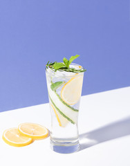 Mojito cocktail with lemon and mint in glass on blue background. summer drink.