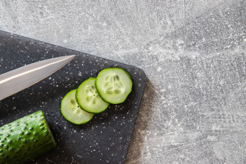Ogórek zielony gruntowy, na desce do krojenia z nożem