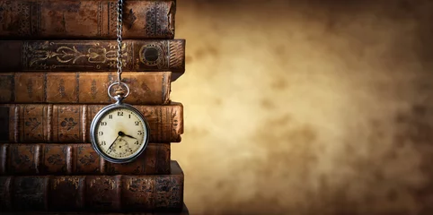 Wall murals Old door Vintage clock hanging on a chain on the background of old books. Old watch as a symbol of passing time. Concept on the theme of history, nostalgia, old age. Retro style.