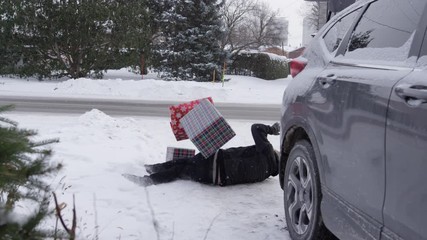 Comical christmas scene man falling when he carries presents from car