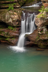 Fototapeta na wymiar Spring Splash - A beautiful Ohio waterfall, the Upper Falls at Old Man’s Cave in Hocking Hills State Park, splashes down a colorful sandstone cliff after spring rains.