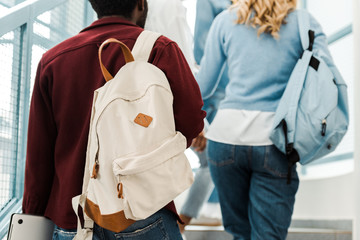 Cropped view of students with backpacks on stairs in university