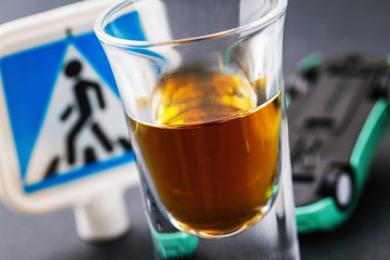Drunk driver, a threat to society. The concept of driving while intoxicated. A glass of whiskey and an inverted machine