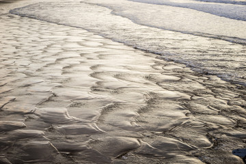 Water textures on the surf and sand of the beach