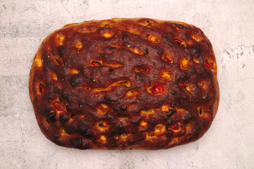 Italian bread with cheese, tomatoes and herbs. Focaccia on the table.