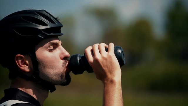 Athlete Drinking Water.Cyclist Drinking Water From Water Bottle.Man In A Helmet With A Bicycle Drinks Water.Close-Up Slow Motion Cyclist Drinking. Close Up Biker Drinking Water Slow Motion.