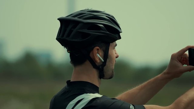 Athlete Taking Photo.Cyclist In Helmet Take Picture On Mobile Phone.Cyclist Taking Photo With Smartphone During Biking Cycling.Portrait Bicyclist Taking Photo.Bicyclist Photographer.Athlete Smartphone