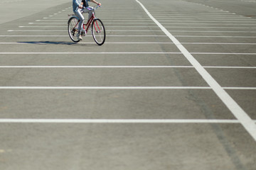 beautiful blonde girl in a denim jacket riding a red vintage bicycle in the parking lot near the new buildings