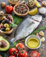 Raw dorado fish with spices and vegetables on the graphite board.