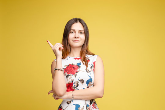 Side view studio portrait of stylish attractive young woman looking away and holding finger. Sudactive feminine model in black with make up plump lips and big eyes holding hand. Concept of style.