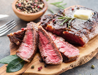 Medium rare Ribeye steak with herbs and a piece of butter on the wooden tray.
