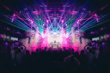  DJ met handen omhoog in een nachtclub met lasers © amacrobert