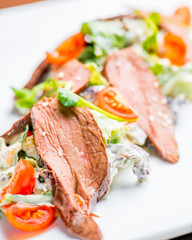 salad with meat fillet on a white plate