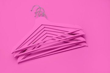 Creative fashion concept. Flat lay top view colored wooden hangers on pink background minimalism style pop-art. Sale discount store shopping concept, design empty hanger. Beauty feminine blog