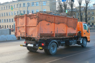 orange car carrying rubbish in a body covered with a net