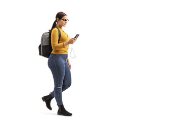 Female student walking and choosing a song from her mobile phone