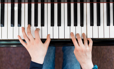 Little girl is playing the grand piano. Top view.