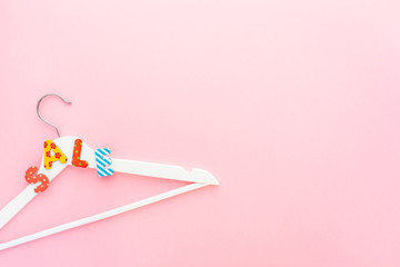 White hangers with sale text on pink background