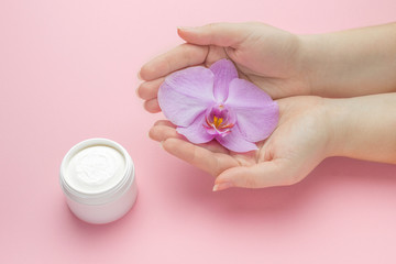 Mockup for natural women cosmetics. Fashion hand art orchide natural cosmetics women, hand care. Creative beauty photo girl sitting at table, contrasting background.