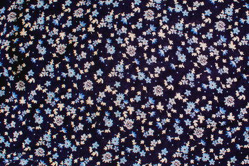 blue small flowers on a dark background on fabric texture fabric
