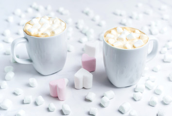 Romantic cozy desk top with two cups of coffee with heart shape marshmallows on marble table.