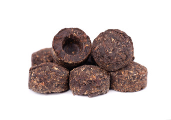 Aromatic black pu-erh tea, isolated on white background. Close up. Fermented and compressed Leaves into bricks. Round flat disc of puer tea. Healthy drink.