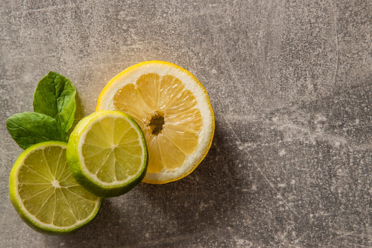 Limonka oraz cytryna w plasterkach na betonowym tle z liśćmi mięty