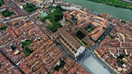 Fototapeta premium Aerial view of Ponte Vecchio bridge on Arno river in Florence city center, Italy. Italian orange roofs from drone near Cathedral. Tuscany.