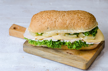 Delicious sandwiches with ham, cheese, salty cucumber and salad over a wooden board on white background.