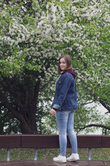 Young beautiful girl stays near an blooming tree